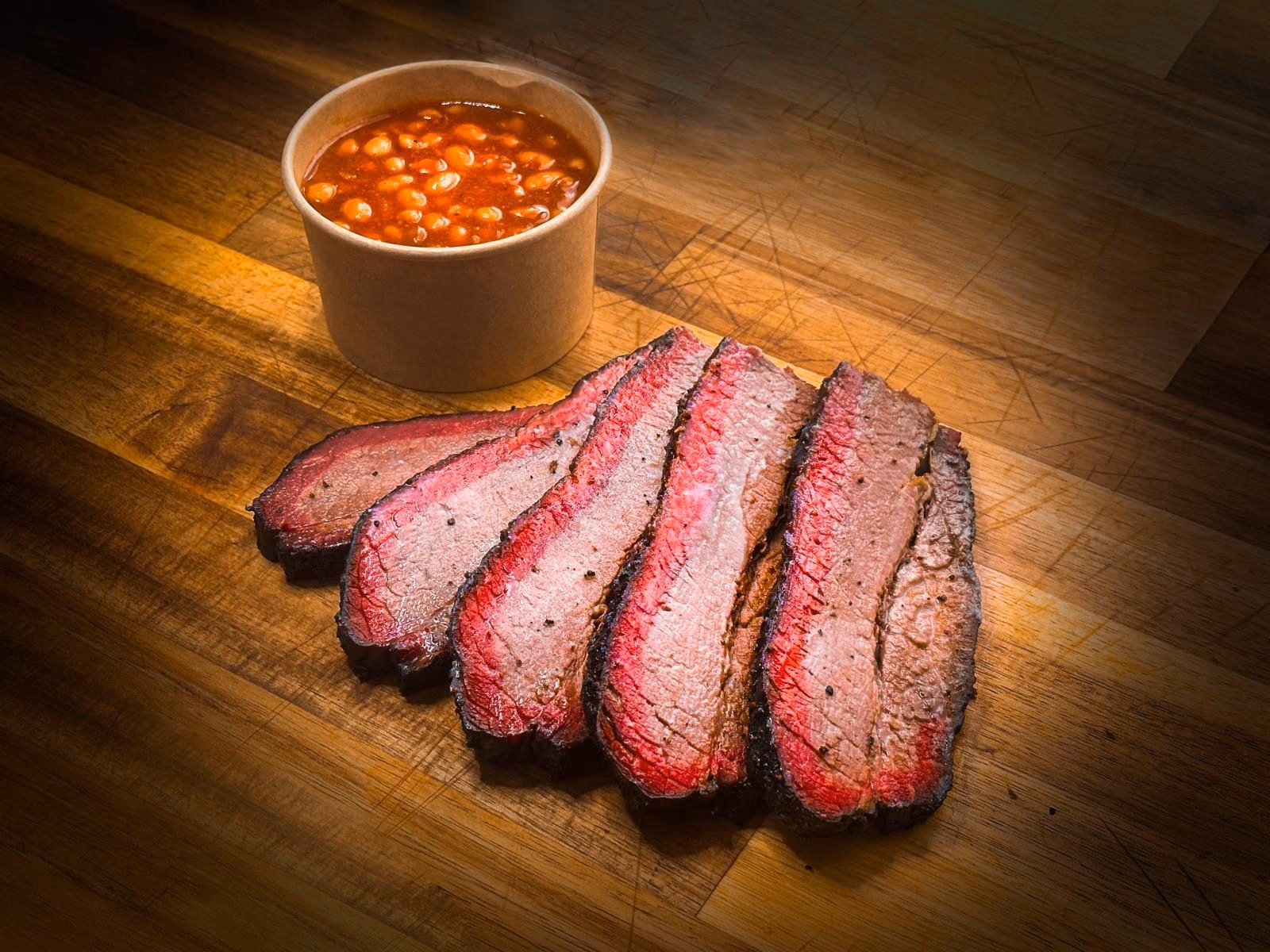 Brisket de bœuf fumé low & slow au chêne et merisier, tranché et servi avec des baked beans