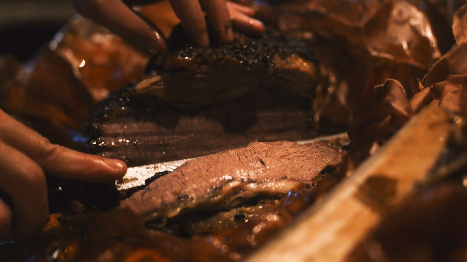 Découpe au couteau d'une viande fumée, gros plan sombre