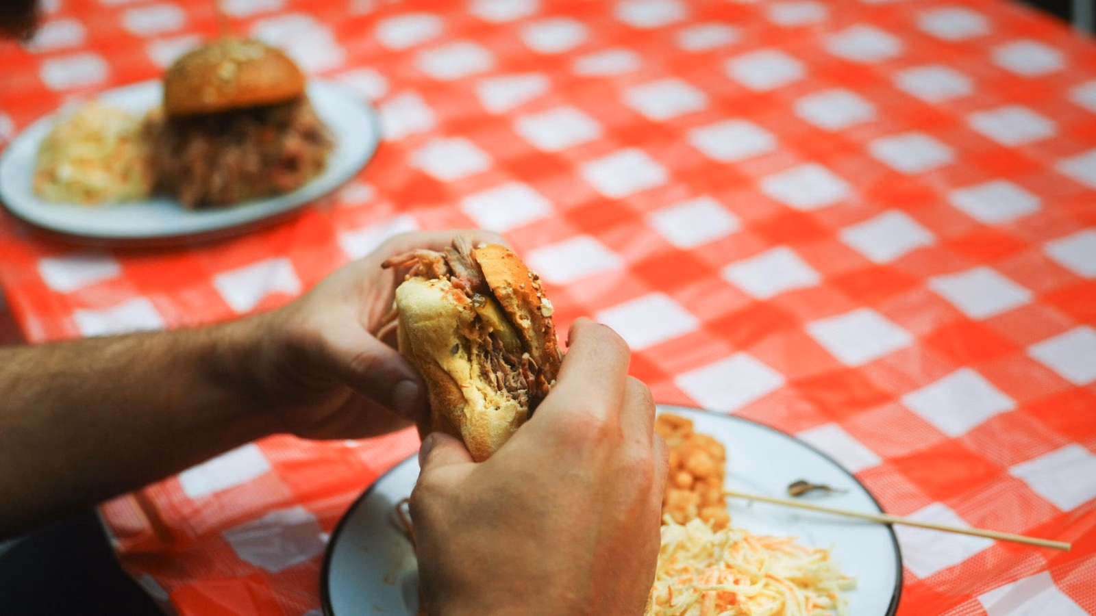 Convive dégustant un burger fumé à pleines mains