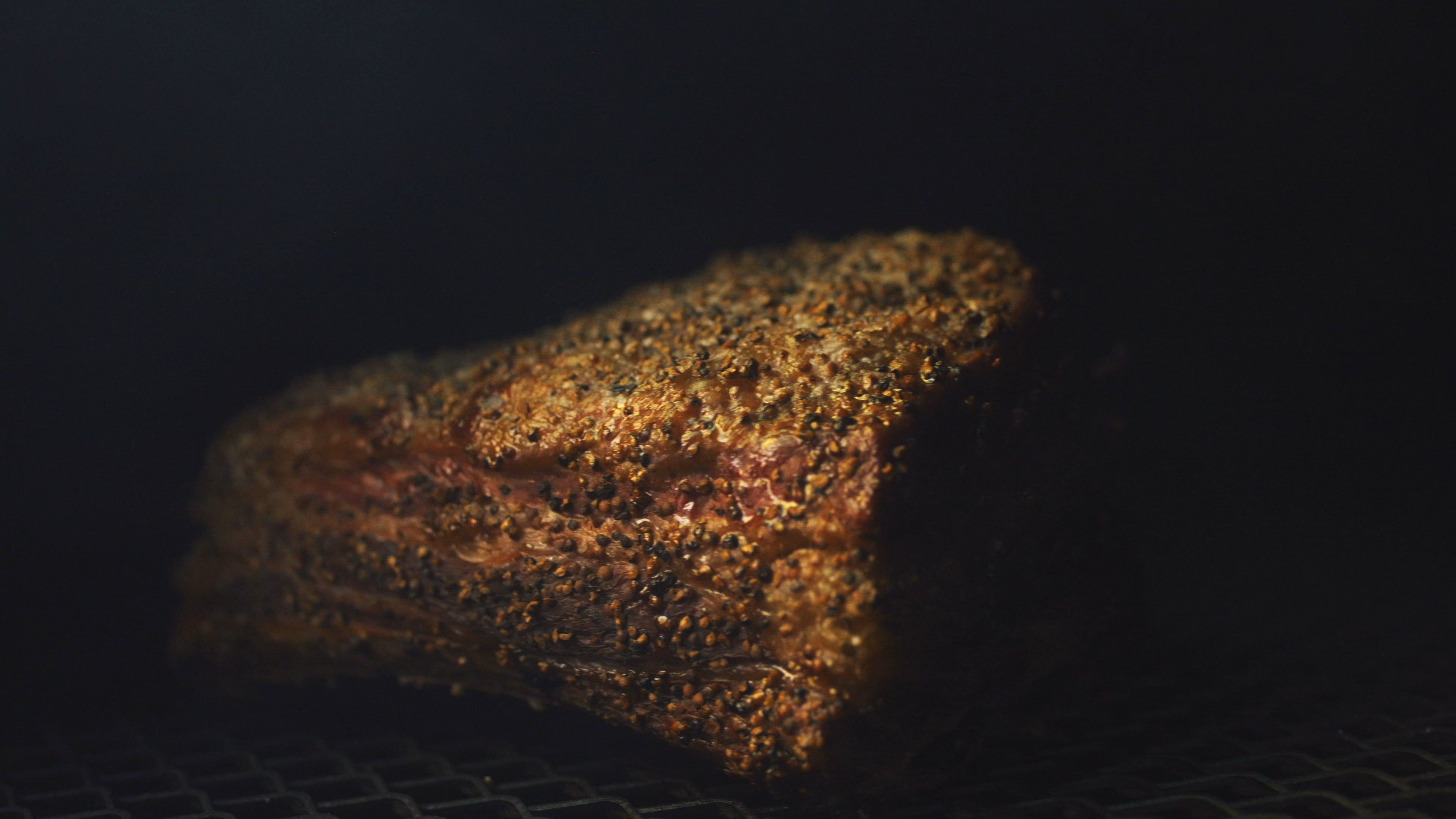 Brisket couvert de son rub d’épices, photographié sur fond noir