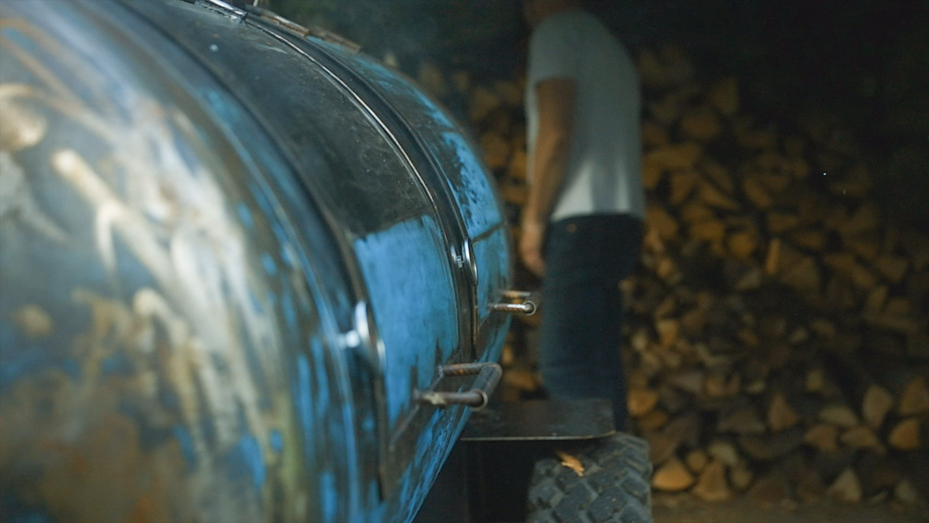 Smoker installé en extérieur à côté d’une corde de bois, avec des personnes autour